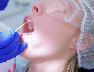 A dentist applying fluoride varnish to a woman’s teeth
