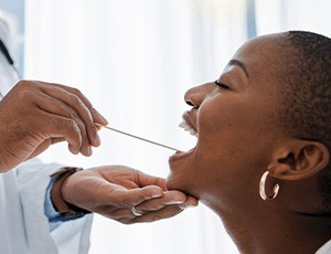 A dentist performing an oral cancer screening on a woman