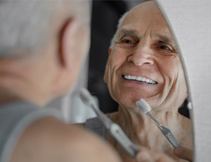 Man brushing his bright pearly whites in the mirror