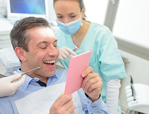 Male patient looking at reflection of smile in handheld mirror