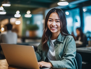 Young woman smiling while working on laptop in office