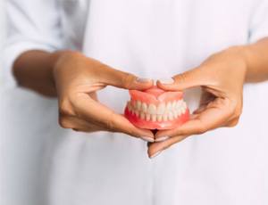 aa dentist holding a pair of dentures