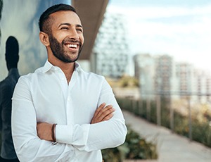 smiling business person crossing their arms and looking over a city