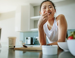 person resting on a kitchen counter and snacking on healthy foods