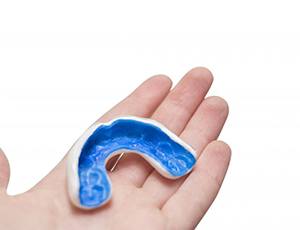 person holding a blue mouthguard in their hand 