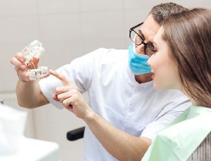 dentist showing a patient a dental implant model 