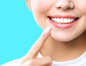 a person pointing at their smile after teeth whitening