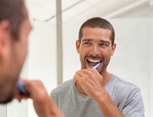 a man brushing his teeth to maintain teeth whitening results
